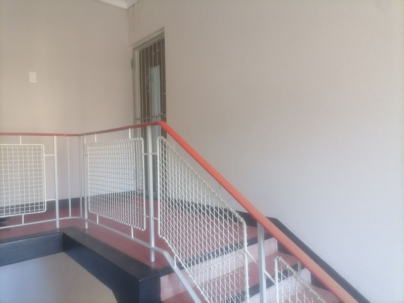 A functional apartment stairwell featuring a metal safety railing and a secure entrance gate.