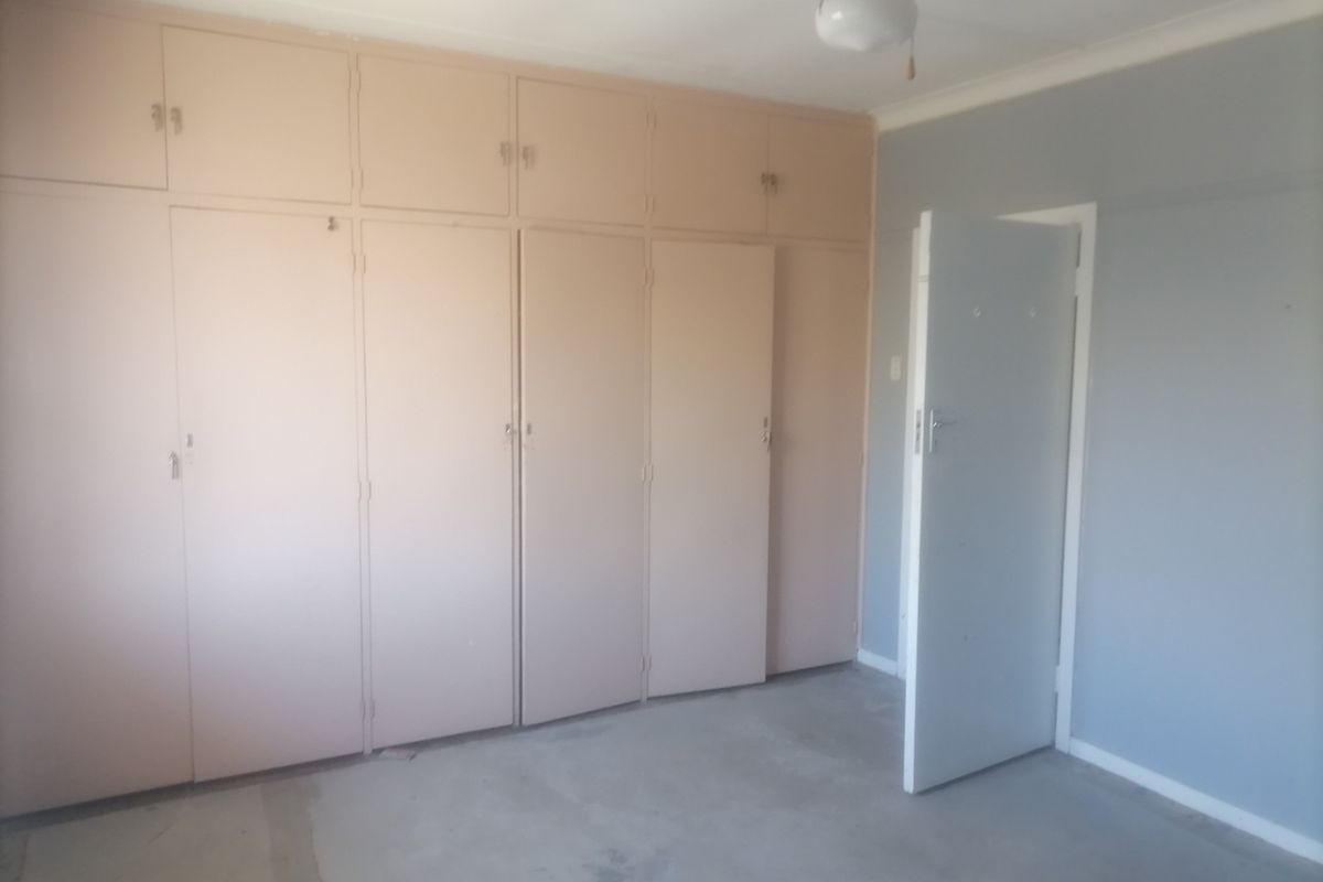An empty bedroom featuring extensive built-in cupboards and a neutral wall finish, offering a blank canvas for renovation or interior design updates.
