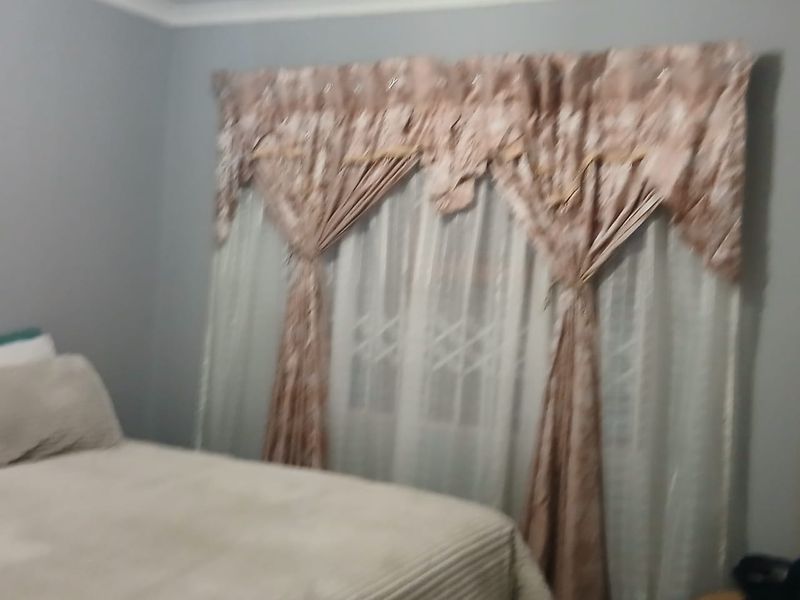 A bedroom featuring a window with security bars and decorative window treatments.
