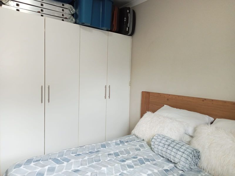 A bedroom featuring a white built-in wardrobe with ample storage space.