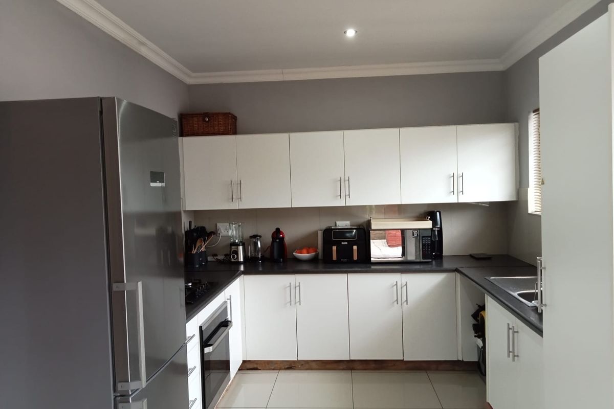 A functional kitchen featuring white cabinetry, dark countertops, tiled flooring, and built-in appliances, offering a clean and practical workspace.
