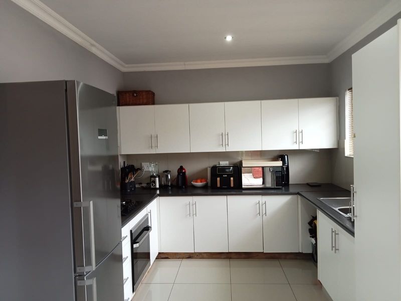 A functional kitchen featuring white cabinetry, dark countertops, tiled flooring, and built-in appliances, offering a clean and practical workspace.