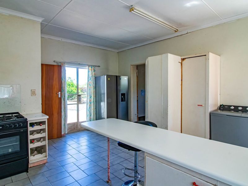 A dated kitchen featuring tiled flooring, a freestanding oven, and built-in cabinetry with a breakfast counter, offering potential for modernization.