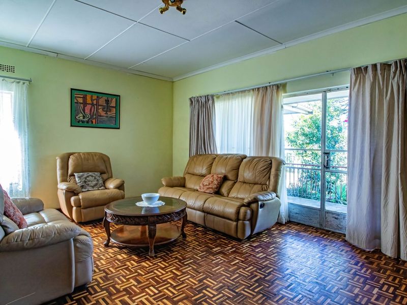 A living room featuring traditional parquet flooring, ceiling tiles, and a sliding glass door providing access to the exterior.