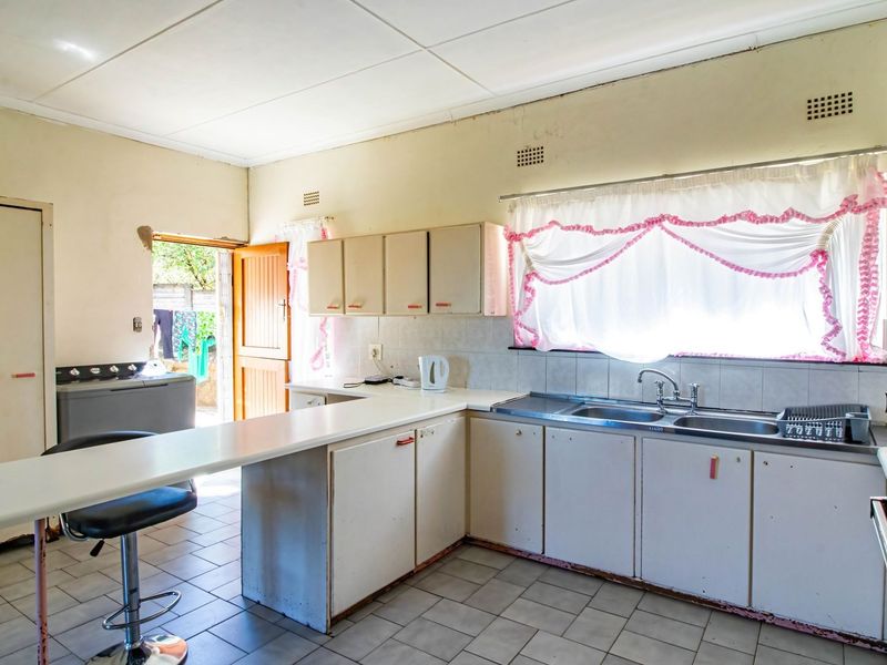 A functional kitchen featuring built-in cabinetry, a double sink, and a breakfast bar, offering potential for modernization and cosmetic updates.