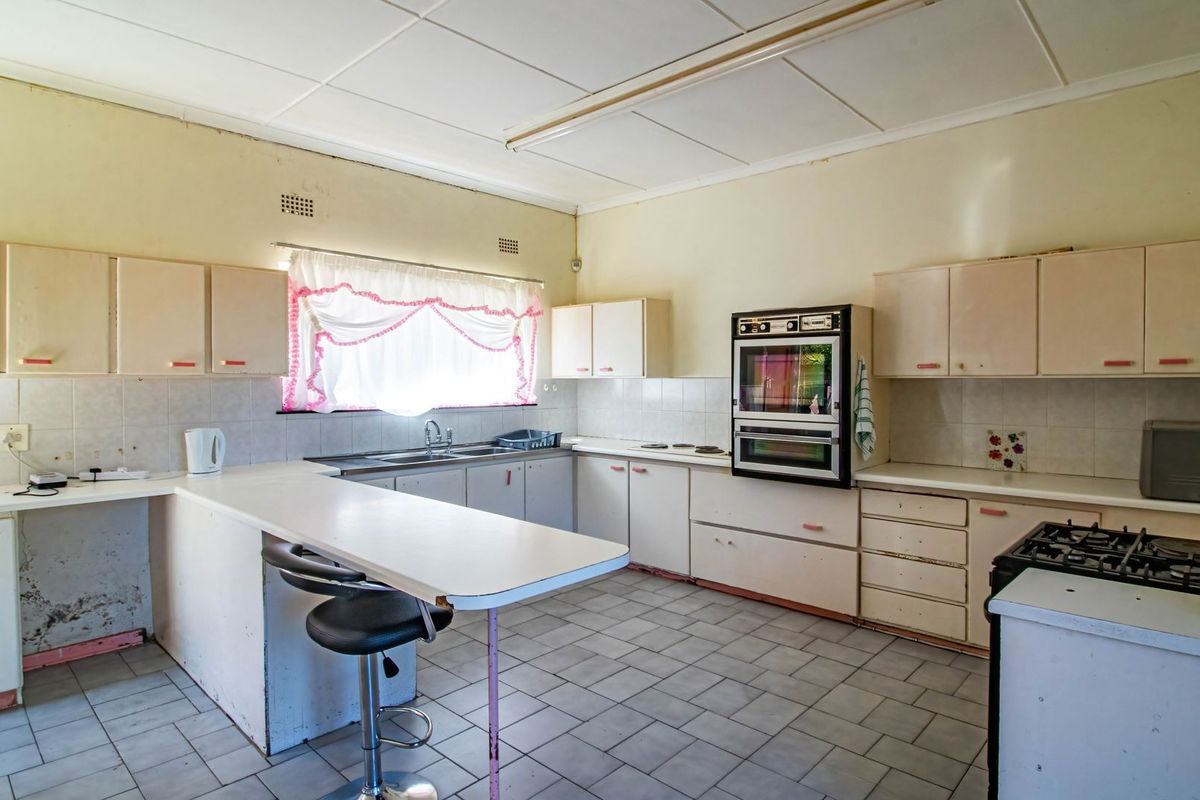 A dated kitchen featuring built-in cabinetry, a double wall oven, and tiled flooring, offering significant potential for a modern renovation.