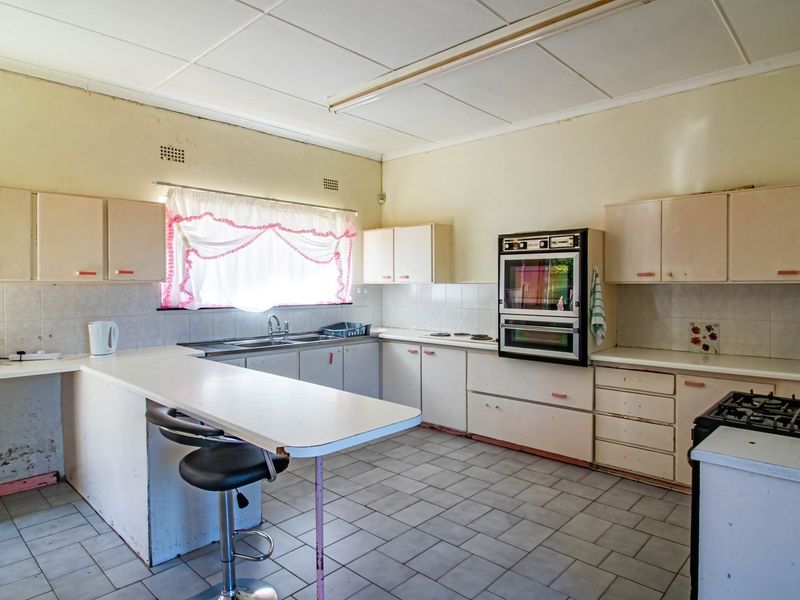 A dated kitchen featuring built-in cabinetry, a double wall oven, and tiled flooring, offering significant potential for a modern renovation.