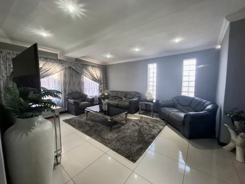 Spacious living room featuring polished tiled flooring, recessed downlighting, and unique glass block windows, creating a bright and contemporary atmosphere.