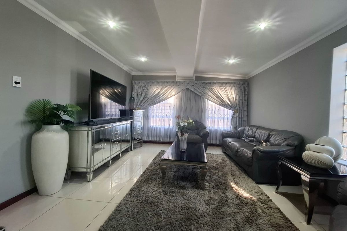 A well-maintained living room featuring tiled flooring, recessed downlighting, and decorative cornicing, creating a bright and comfortable space.