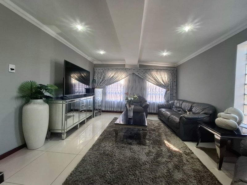 A well-maintained living room featuring tiled flooring, recessed downlighting, and decorative cornicing, creating a bright and comfortable space.