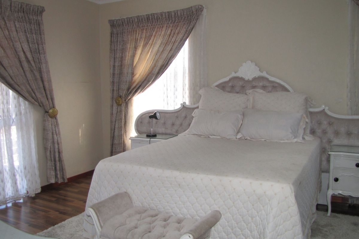 A well-lit bedroom featuring laminate flooring and neutral wall tones, providing a comfortable and functional sleeping space.