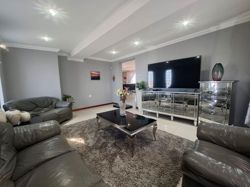 A well-maintained living room featuring tiled flooring, recessed ceiling lighting, and decorative coved cornicing, providing a comfortable and neutral living space.
