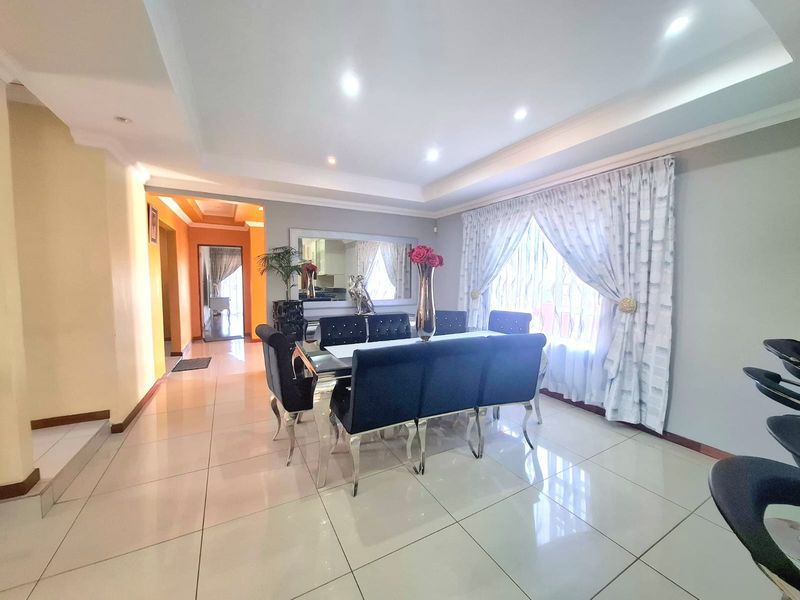 A bright and spacious dining room featuring polished tiled flooring, recessed ceiling lighting, and a coved ceiling design.