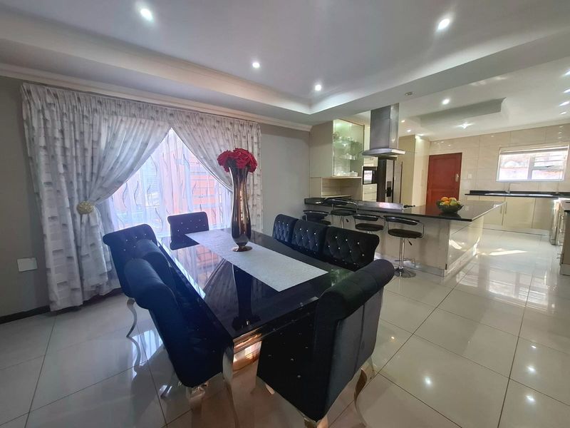 Spacious open-plan living and dining area featuring a modern kitchen with a central island, sleek cabinetry, and polished tiled flooring throughout.
