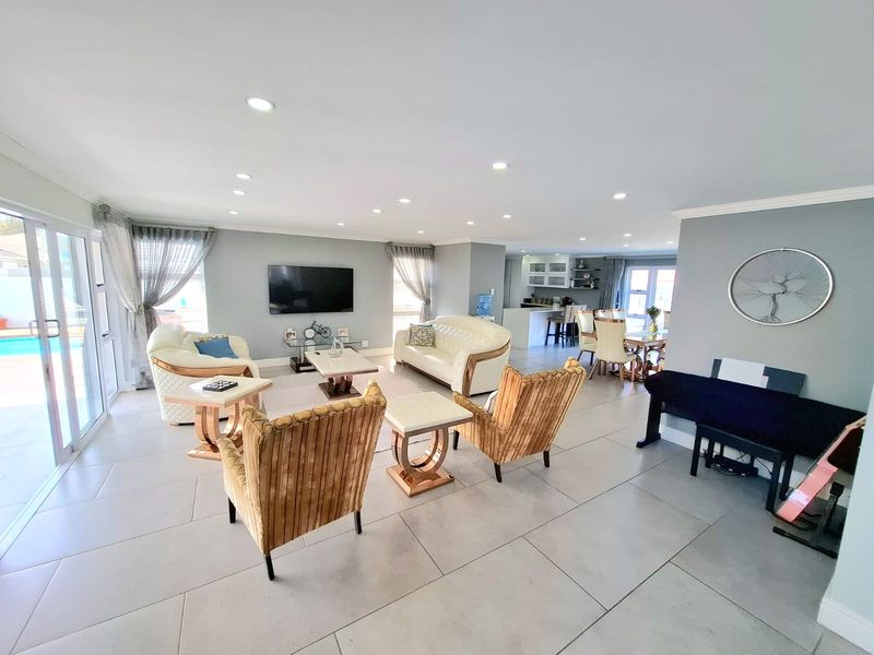 Spacious open-plan living and dining area featuring large format floor tiles, recessed lighting, and seamless flow to the outdoor patio area.