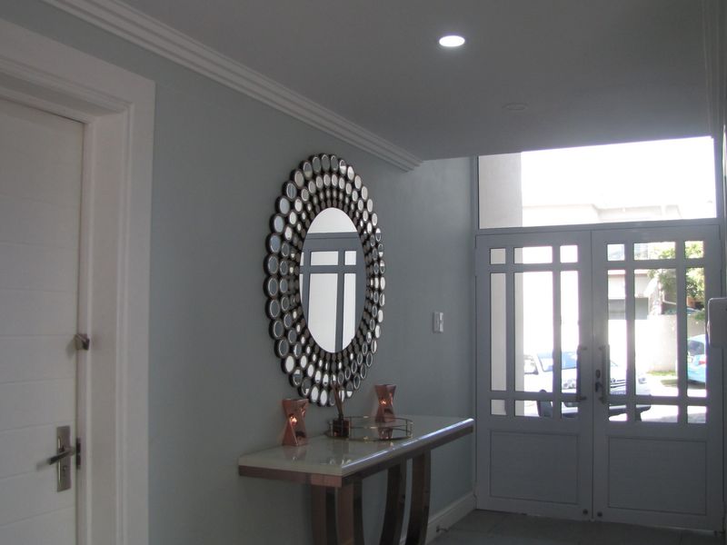 A bright and welcoming entrance hall featuring elegant crown molding, recessed downlights, and a double glass-paneled front door.