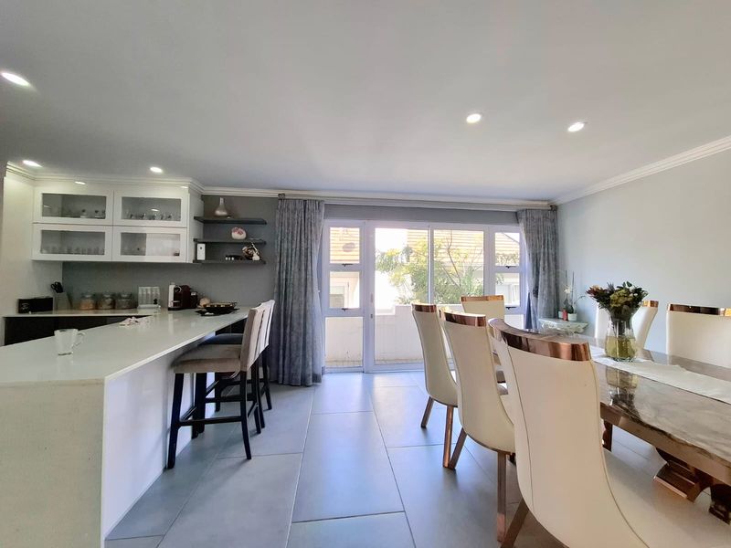 Spacious open-plan living and dining area featuring a modern kitchen island, sleek tiled flooring, and large sliding doors leading to an outdoor space.