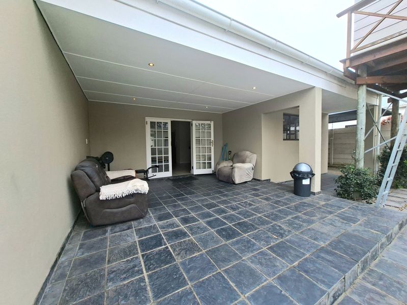 A covered patio area featuring slate tile flooring, recessed lighting, and direct access to the interior through double french doors.