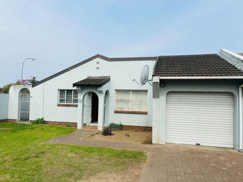 Front elevation of a townhouse featuring a single garage, paved driveway, and a covered entrance with security gate.