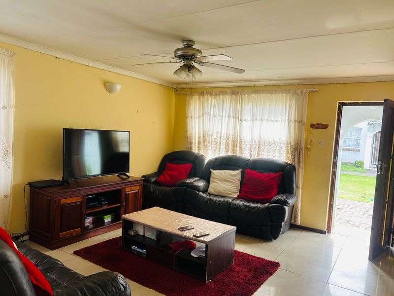 A living room featuring tiled flooring, a ceiling fan, and direct access to the exterior, requiring cosmetic updates to improve its overall condition.