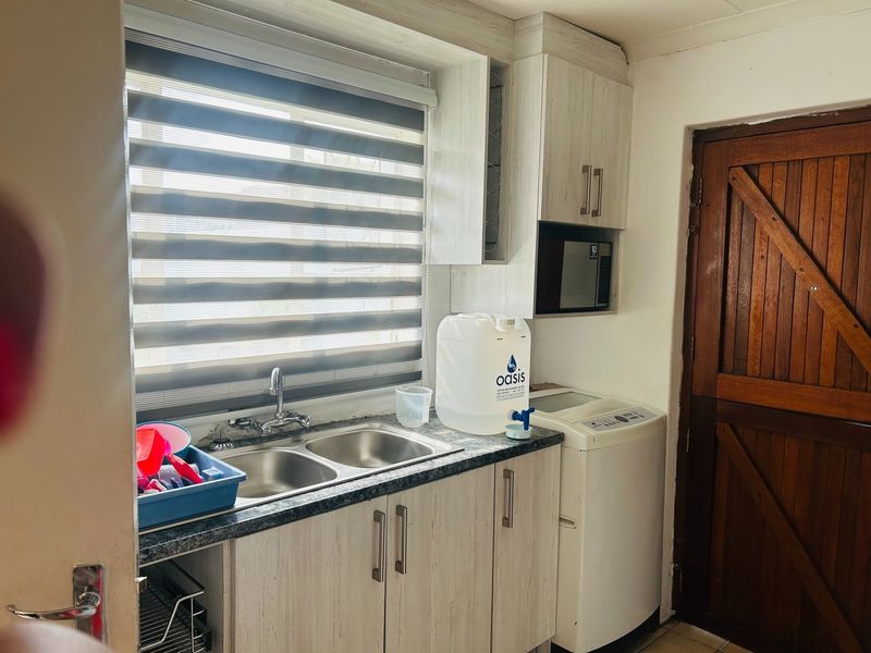 Functional laundry area featuring laminate cabinetry, a double basin stainless steel sink, and a built-in microwave space.