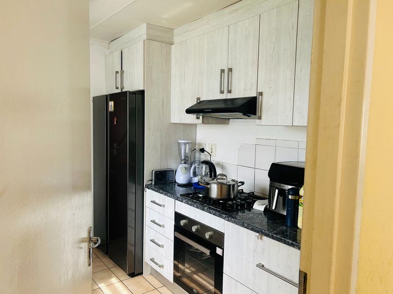 Compact kitchen featuring light wood-grain cabinetry, granite-look laminate countertops, a gas hob, built-in oven, and extractor fan.