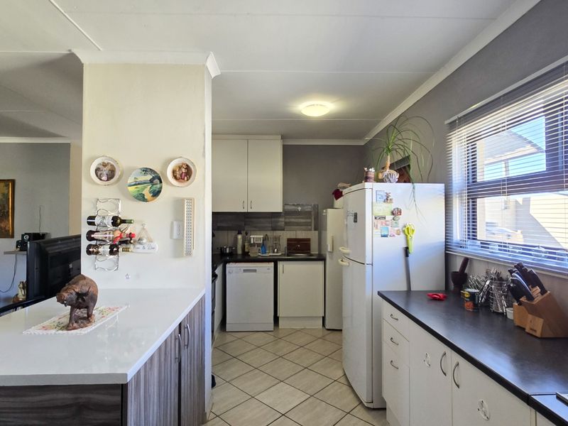 Open-plan kitchen area featuring built-in cabinetry, laminate countertops, and tiled flooring, seamlessly connected to the adjacent living space.
