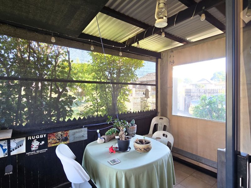 A covered patio area featuring corrugated roofing, shade netting, and tiled flooring, providing a functional outdoor entertainment space.