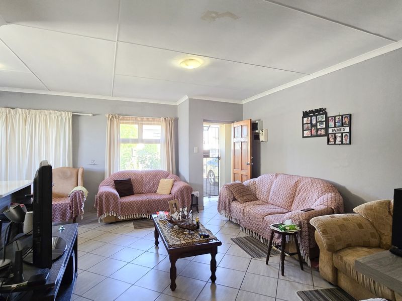 A living room featuring tiled flooring and a ceiling with visible water staining, providing a functional space with potential for cosmetic updates.