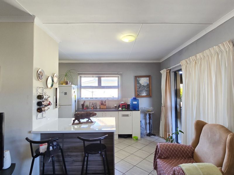 Open plan living and kitchen area featuring tiled flooring, functional cabinetry, and sliding glass doors providing access to the outdoor space.