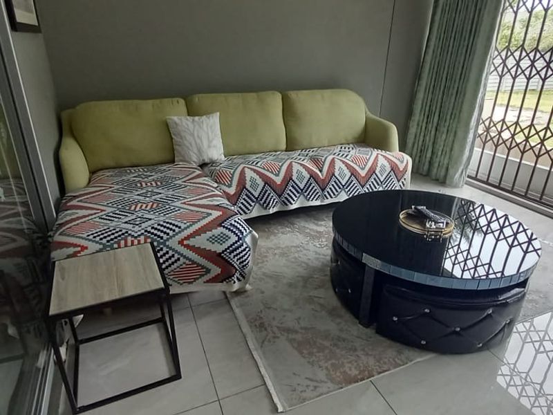 A living room area featuring tiled flooring and a large sliding glass door with an integrated security gate, providing access to the outdoor space.