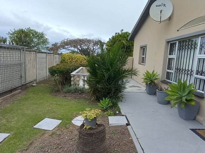 Front exterior view of the property featuring a concrete walkway, security gate, and boundary wall with a sliding gate.