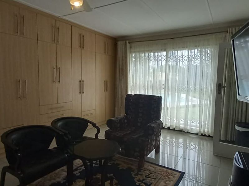 Spacious bedroom featuring extensive built-in cabinetry, tiled flooring, and direct access to the outdoor area through a sliding glass door.