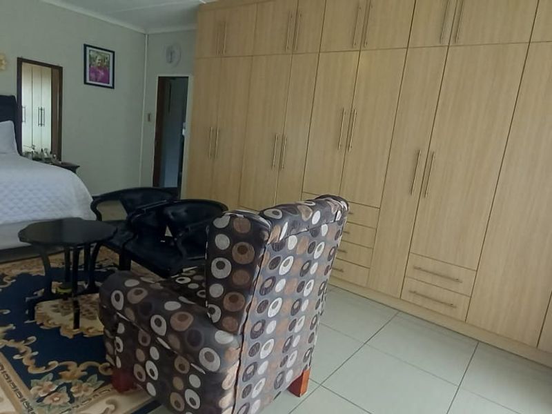 Spacious bedroom featuring extensive built-in wooden cabinetry and neutral tiled flooring, offering ample storage and a functional layout.