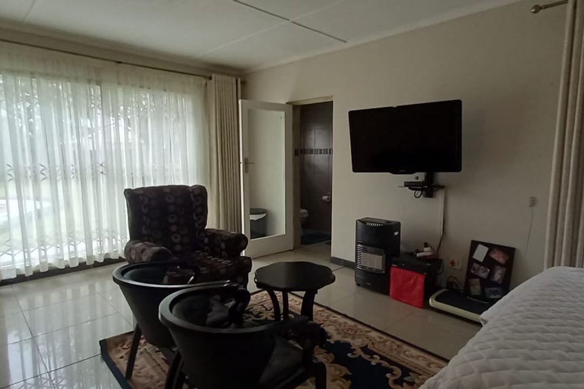 Spacious bedroom featuring tiled flooring, built-in cupboards, and a sliding glass door providing access to the exterior.
