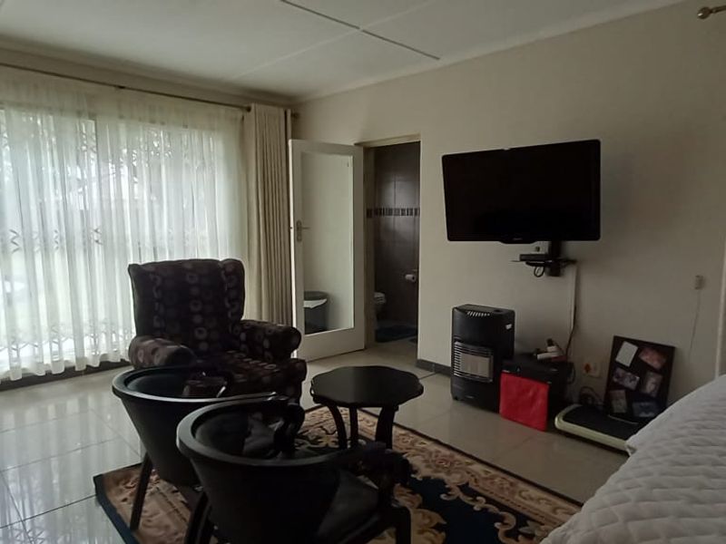 Spacious bedroom featuring tiled flooring, built-in cupboards, and a sliding glass door providing access to the exterior.