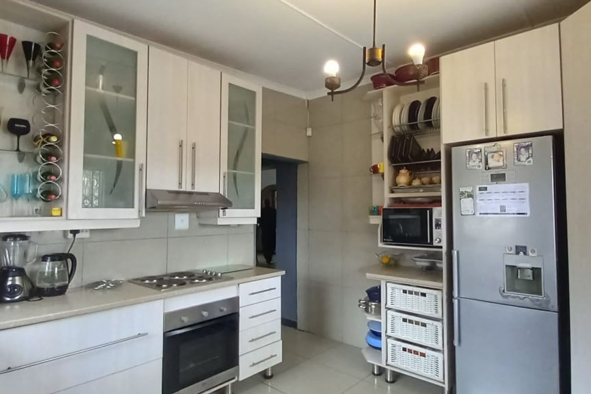 A functional kitchen featuring light-toned cabinetry, built-in oven and hob, tiled splashbacks, and tiled flooring, offering a practical layout for daily meal preparation.