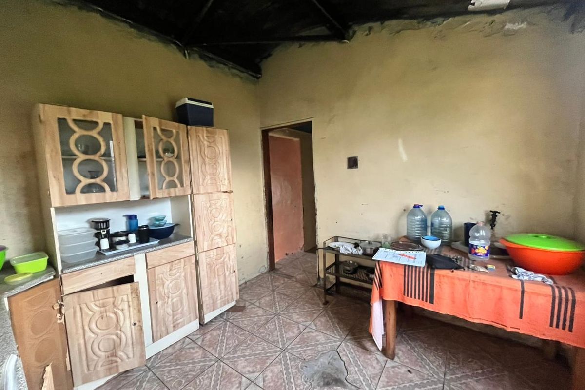 A dated kitchen area featuring built-in wooden cabinetry and tiled flooring, requiring significant renovation and cosmetic updates to improve its condition and functionality.