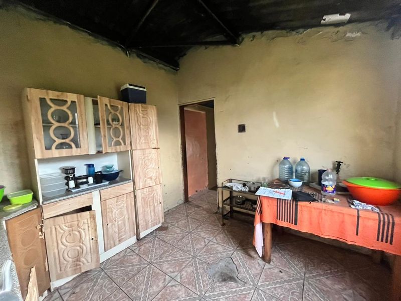 A dated kitchen area featuring built-in wooden cabinetry and tiled flooring, requiring significant renovation and cosmetic updates to improve its condition and functionality.