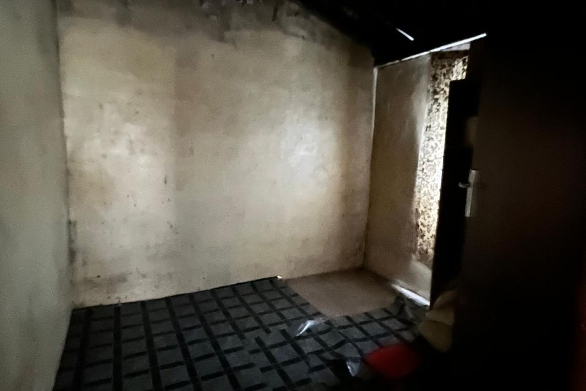 A vacant bedroom space requiring significant renovation and repair to wall and floor finishes to restore it to a habitable condition.