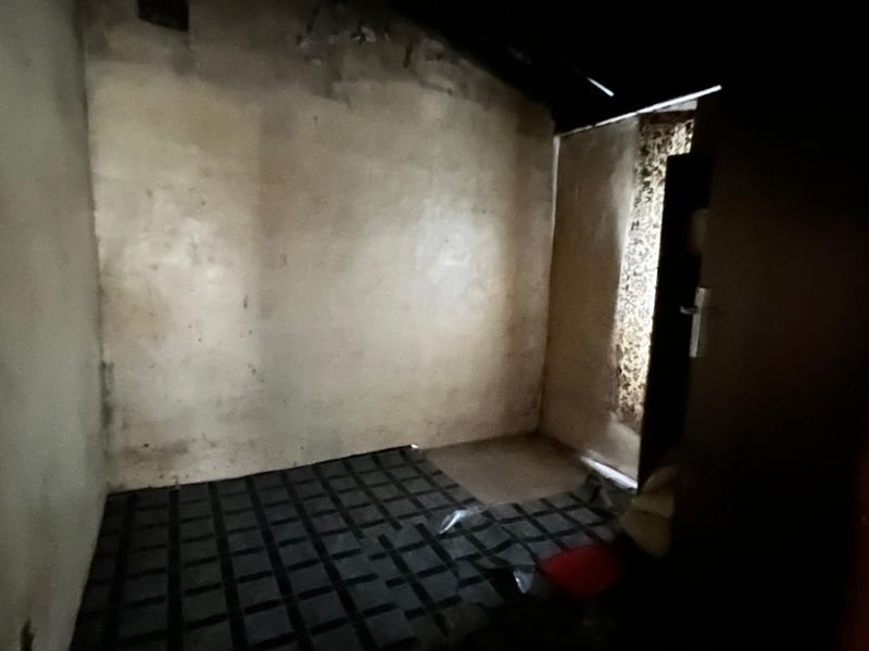 A vacant bedroom space requiring significant renovation and repair to wall and floor finishes to restore it to a habitable condition.