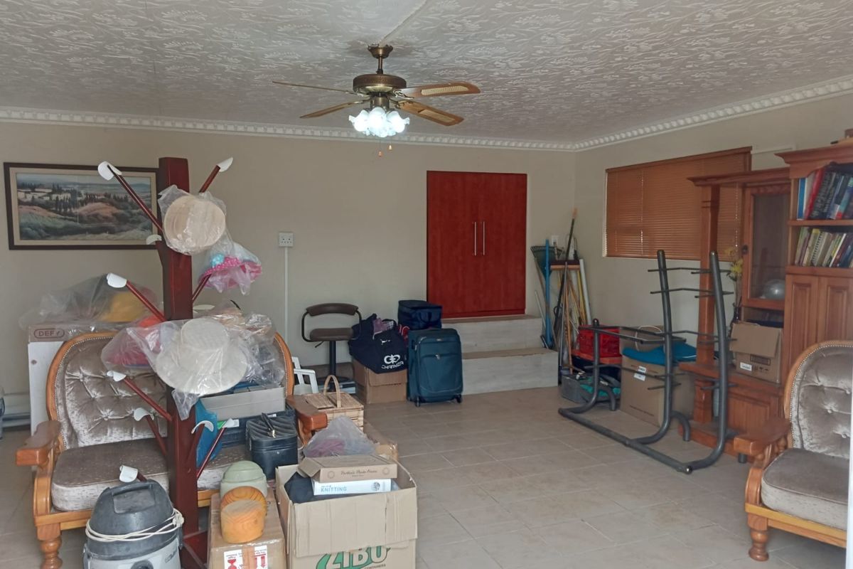 A living area featuring tiled flooring, a ceiling fan, and textured ceiling finishes, currently used for storage.