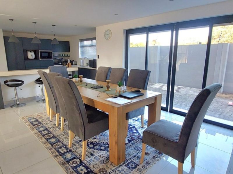 Open-plan dining and kitchen area featuring modern cabinetry, a central island, tiled floors, and large sliding doors providing access to the outdoor space.