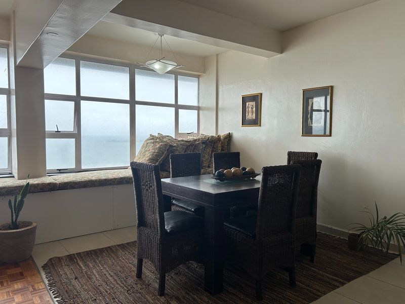 Dining area featuring a built-in window seat with ocean views, large windows, and parquet flooring.
