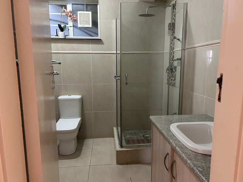 A clean, functional bathroom featuring a glass-enclosed shower, modern toilet, and a vanity unit with a granite countertop.