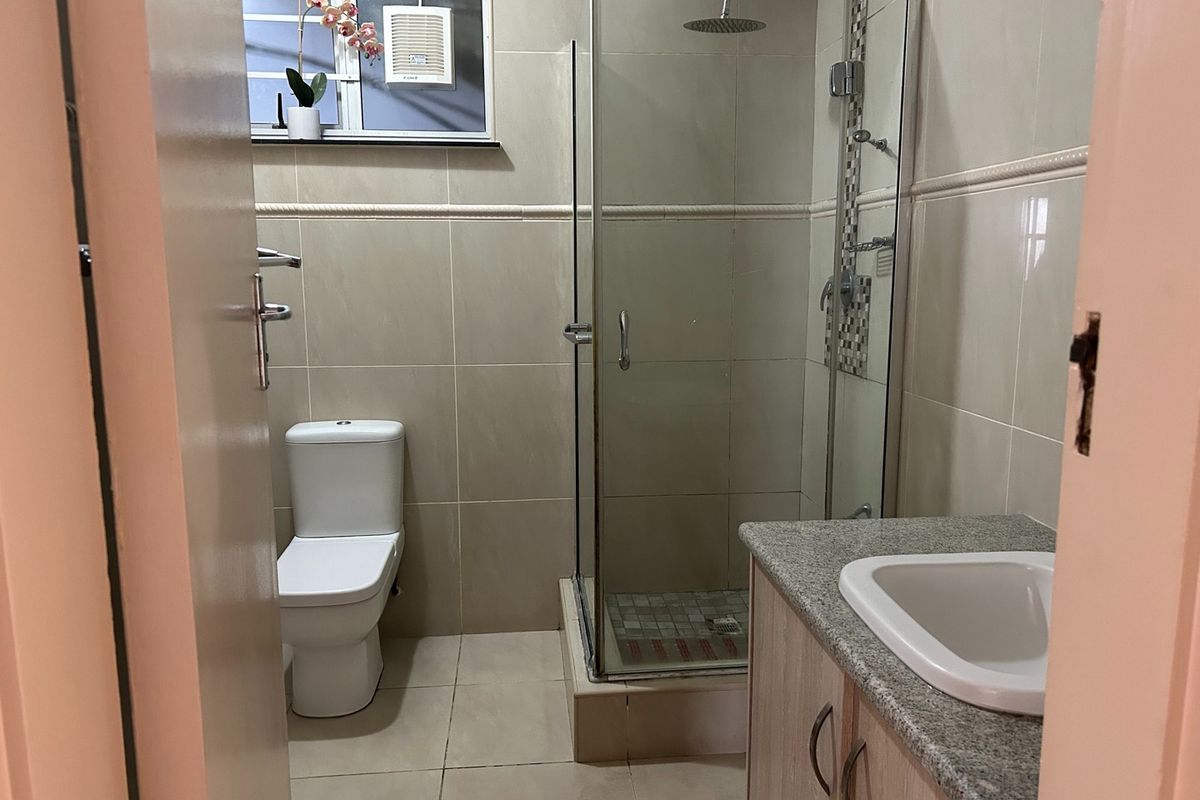 A clean, functional bathroom featuring a glass-enclosed shower, modern toilet, and a vanity unit with a granite countertop.