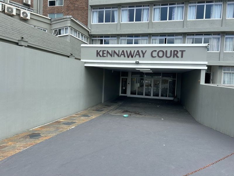 The front entrance of Kennaway Court featuring a covered driveway, building signage, and glass access doors to the apartment complex.