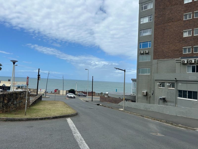 Street view showing the approach to the apartment building with coastal views in the background.