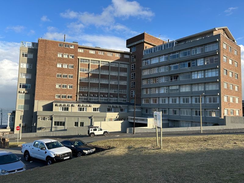 Exterior view of Kenway Court, a multi-story apartment building featuring a brick and concrete facade with established parking areas.