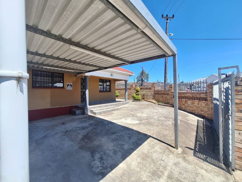 Front exterior view featuring a covered carport, concrete driveway, and secure brick boundary walling.